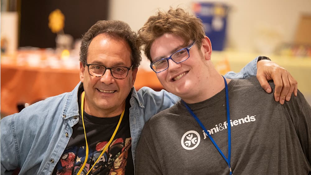 Two men pose together, smiling at the camera.