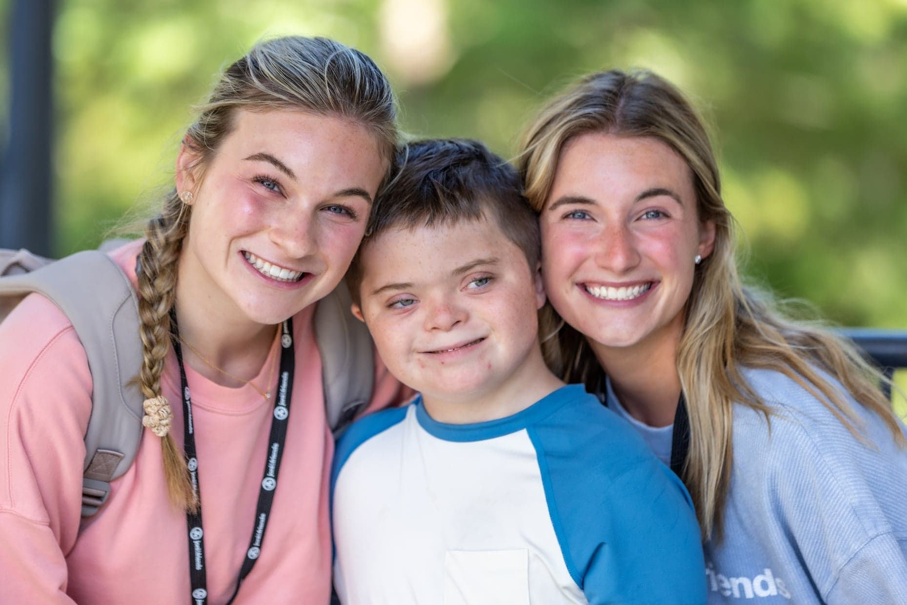 A boy  between two smiling women volunteers from Joni and Friends, all posing for the camera.