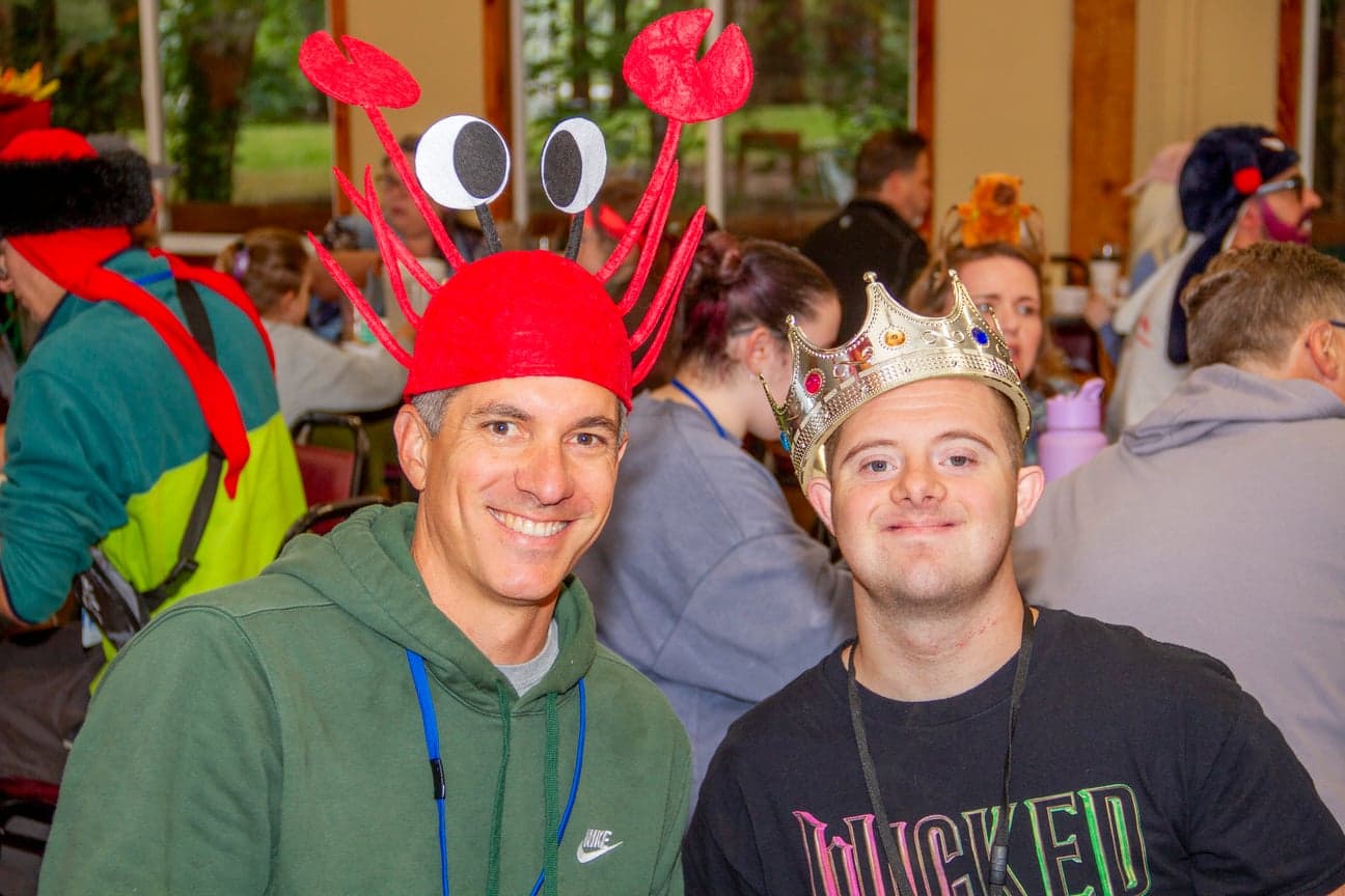 two men smiling for the camera with people in the background