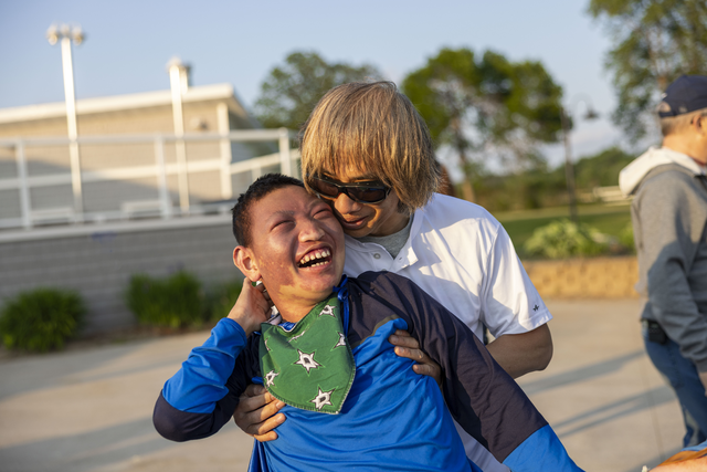 A boy with a disability enjoying his time while his father supports him from behind.