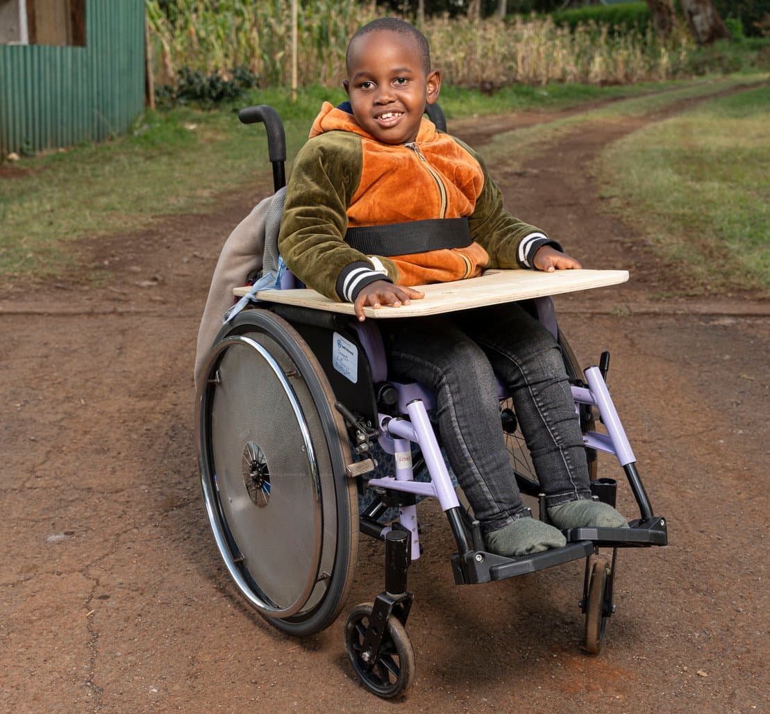 A boy in a wheelchair smiling directly at the camera.