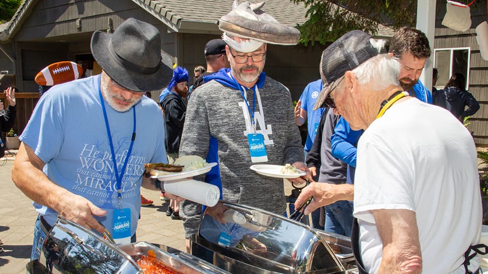 People serving themselves from a silver buffet tray.
